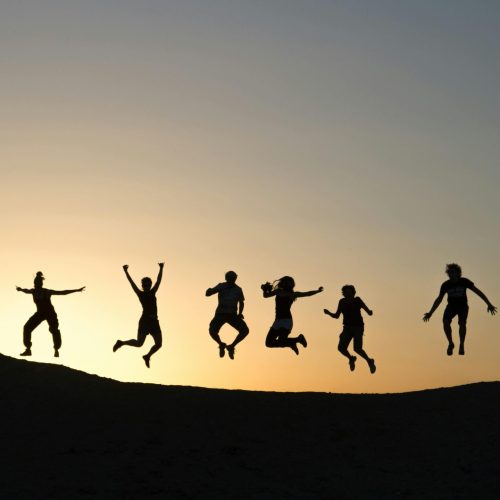 Equilibrio e bem-estar Em um pôr-do-sol estão vária pessoas pulando felizes